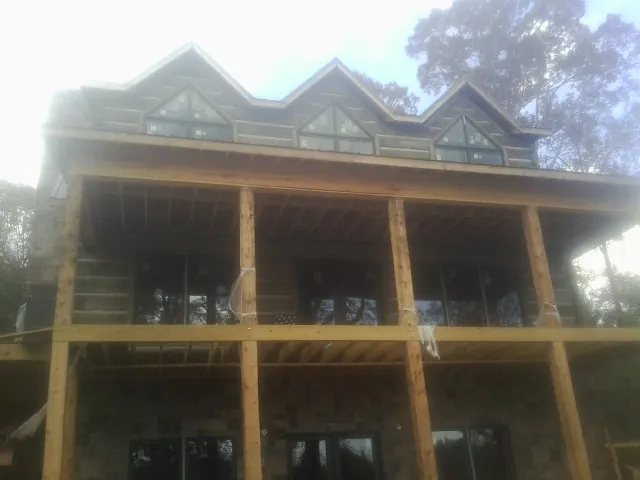 Dormers and porch framing on a large log home under construction — Roof Coating work by our crew in South Sioux City