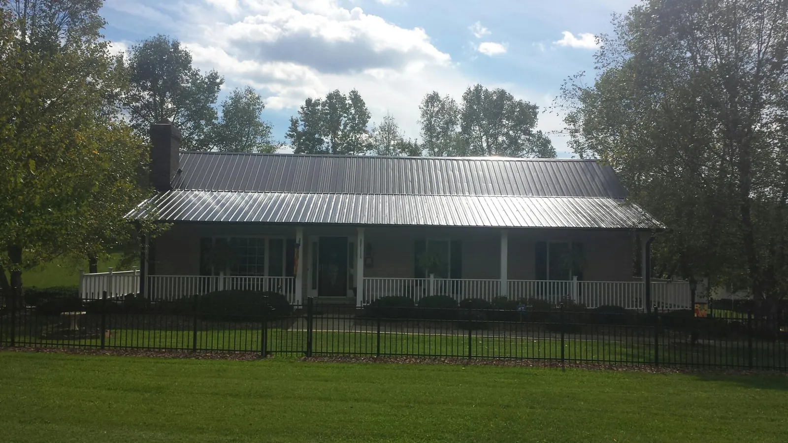 Gray metal roof on a brick ranch with a full width front porch — Gutter Guard Installation work by our crew in South Sioux City