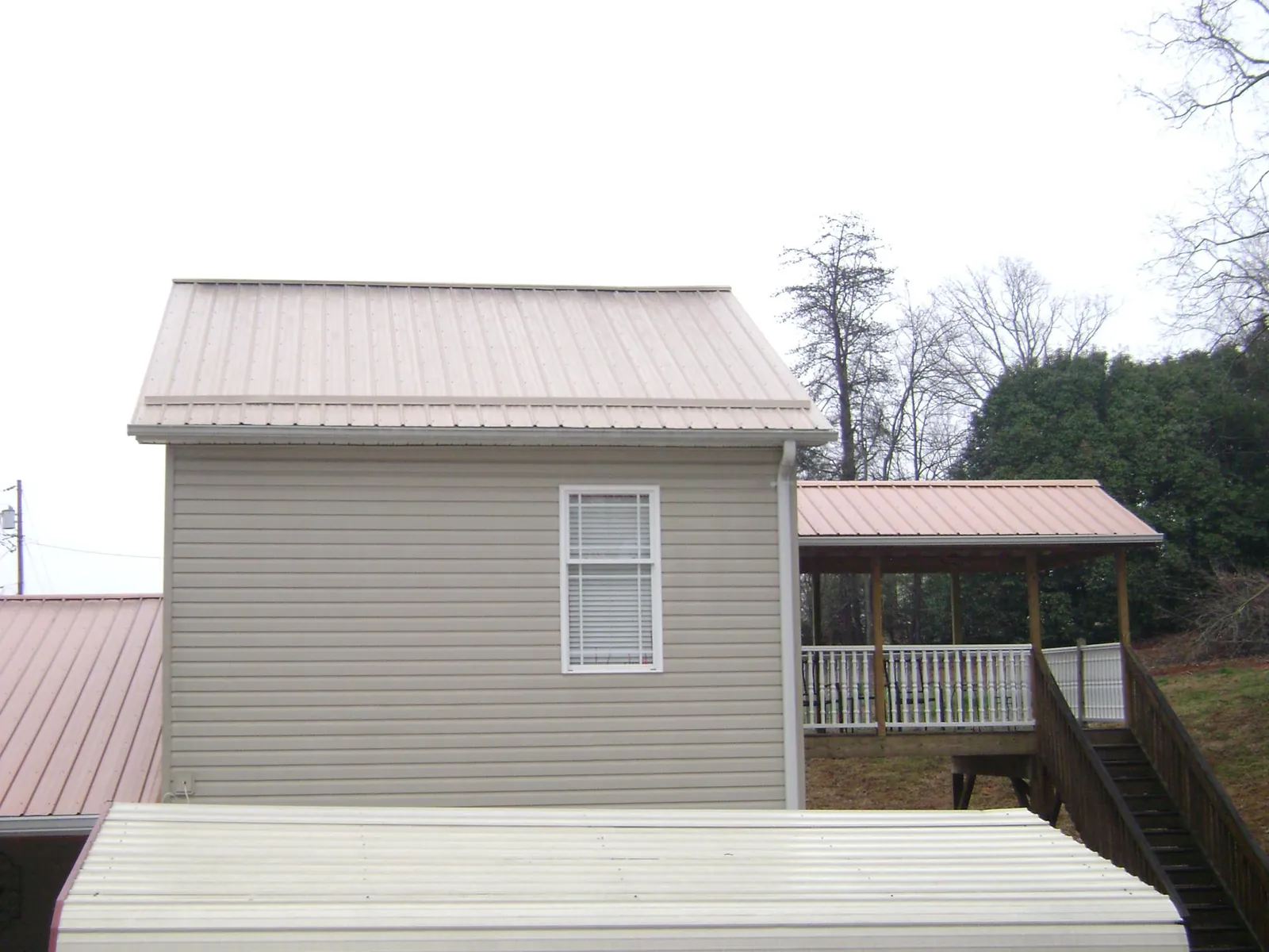 Tan metal roofs on a two story addition and attached porch, from a Roof Replacement job in South Sioux City