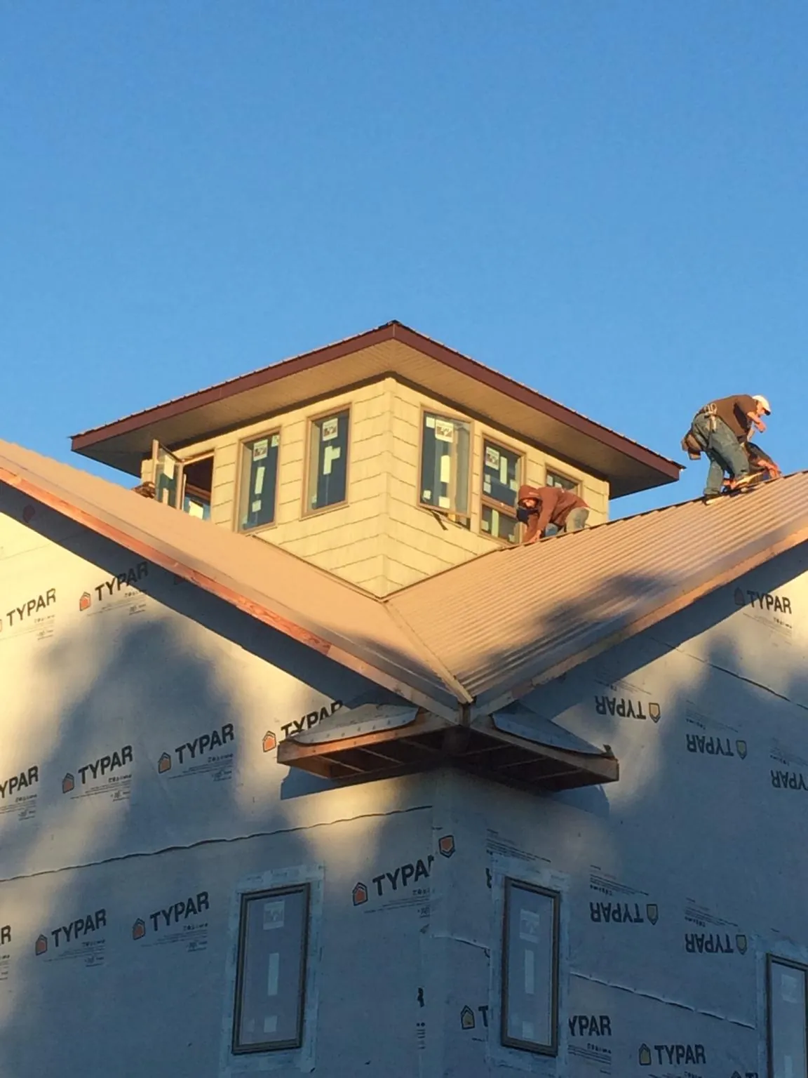 Roofers working around a rooftop cupola on a new metal roof at sunset — Roof Waterproofing in South Sioux City by Roofing Brothers